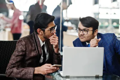 two-indian-business-man-suits-sitting-office-cafe-looking-laptop